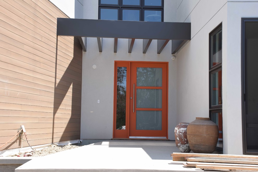 Idéer för en mellanstor modern ingång och ytterdörr, med vita väggar, betonggolv, en enkeldörr och en orange dörr