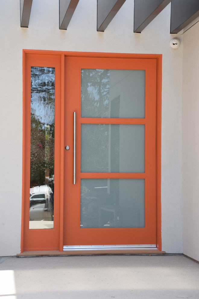 Inredning av en modern mellanstor ingång och ytterdörr, med vita väggar, betonggolv, en enkeldörr och en orange dörr