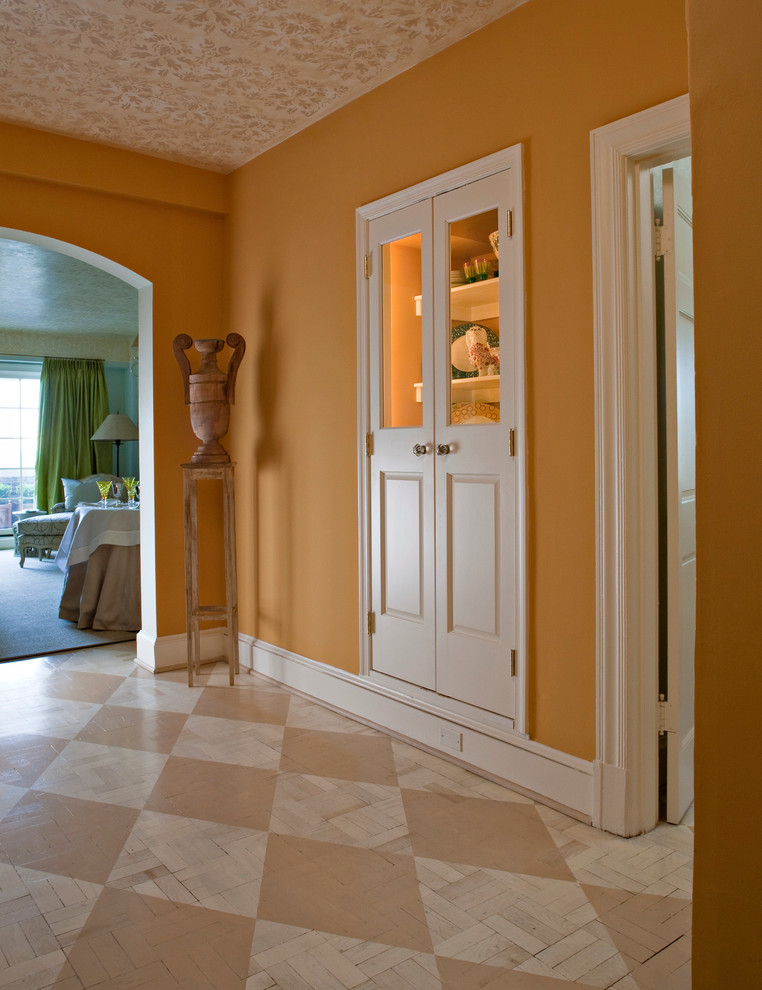 На фото: фойе среднего размера в стиле неоклассика (современная классика) с оранжевыми стенами и деревянным полом