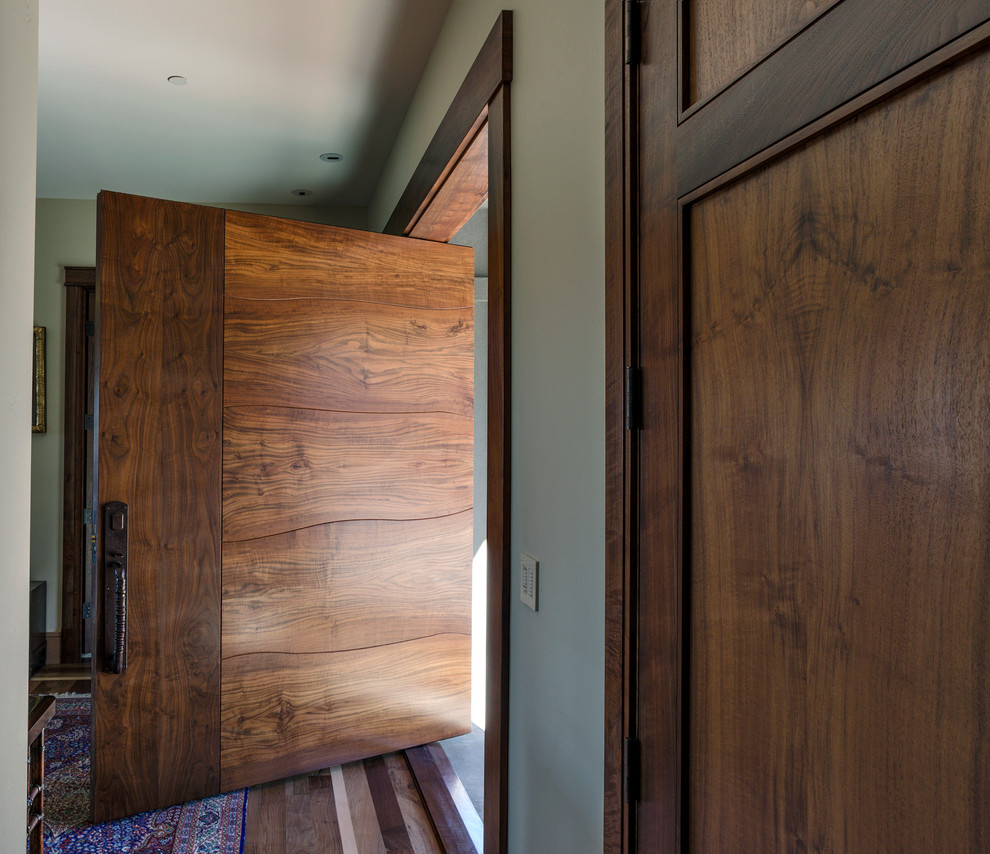 Große Moderne Haustür mit grüner Wandfarbe, braunem Holzboden, Drehtür und dunkler Holzhaustür in Sonstige
