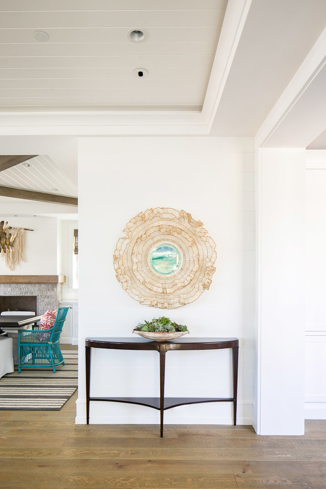 Example of a mid-sized island style medium tone wood floor and brown floor entryway design in Orange County with white walls and a medium wood front door