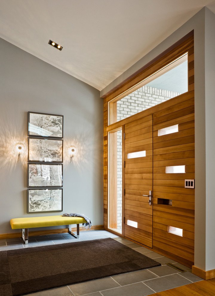 Immagine di un ingresso o corridoio minimalista con una porta in legno bruno e pareti grigie