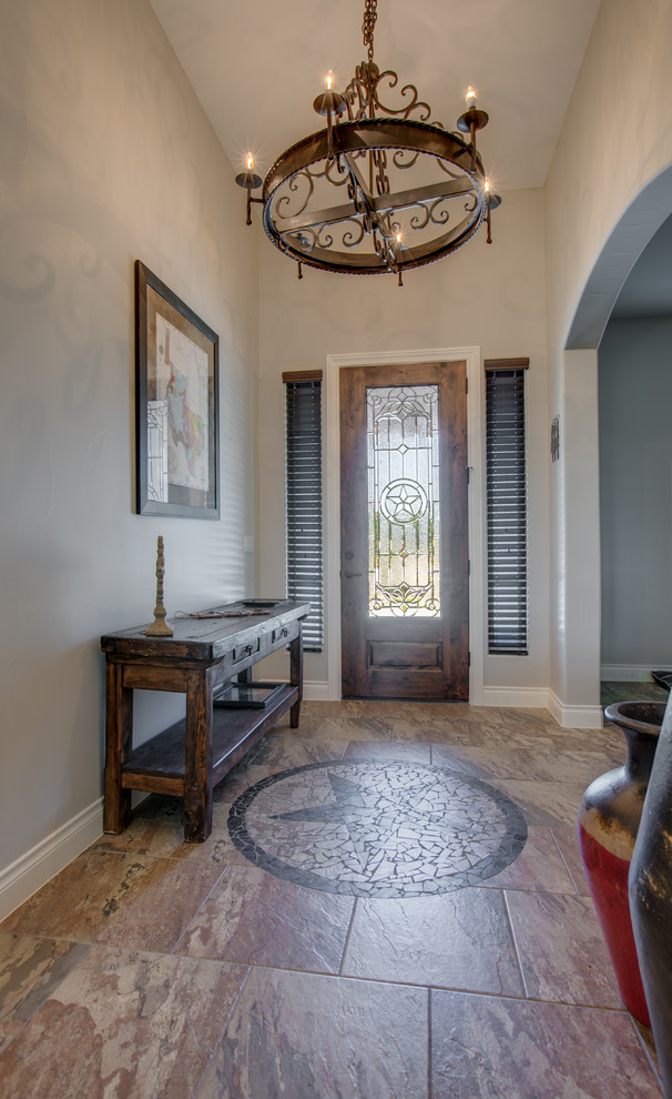 Example of a mid-sized tuscan porcelain tile and brown floor entryway design in Austin with gray walls and a glass front door