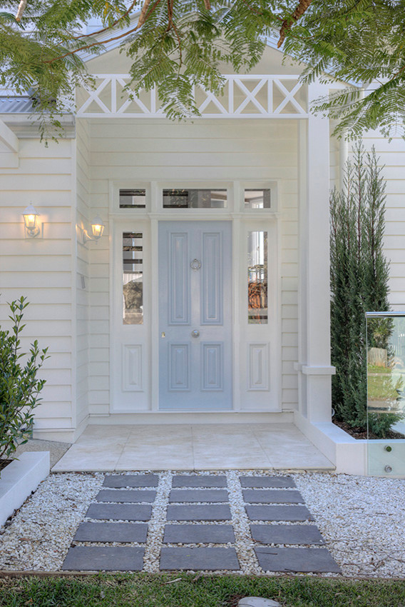 Réalisation d'une porte d'entrée tradition de taille moyenne avec un mur blanc, un sol en calcaire, une porte simple et une porte bleue.