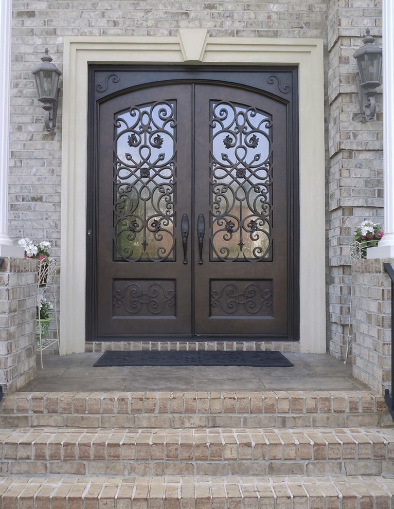 Réalisation d'une grande porte d'entrée tradition avec une porte double et une porte marron.