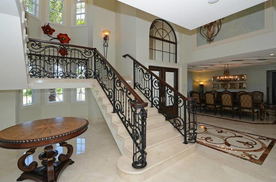 Example of a large tuscan ceramic tile and beige floor entryway design in Miami with beige walls and a glass front door