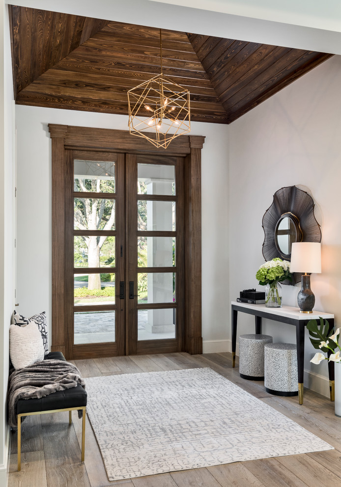 Design ideas for a classic foyer in Other with white walls, a double front door, a dark wood front door, grey floors, light hardwood flooring and feature lighting.