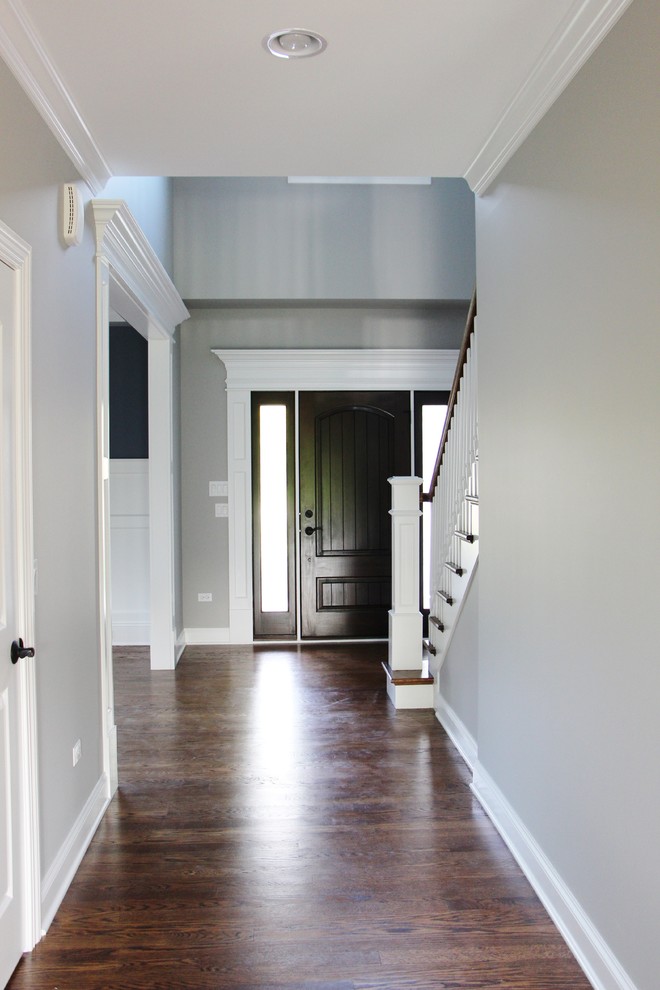 Example of a mid-sized transitional medium tone wood floor entryway design in Chicago with gray walls and a dark wood front door