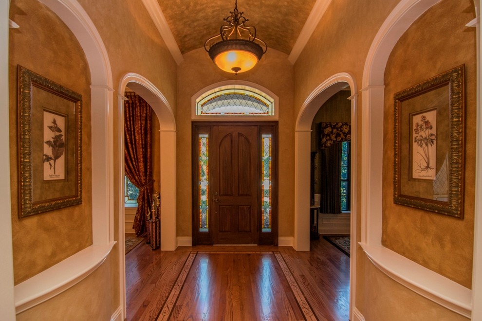 Cette image montre une petite porte d'entrée traditionnelle avec un mur marron, un sol en bois brun, une porte simple, une porte en bois foncé et un sol marron.