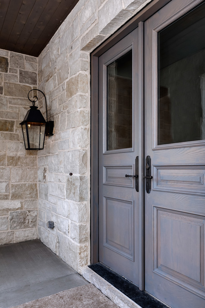 Ejemplo de puerta principal tradicional grande con paredes grises, suelo de cemento y puerta doble