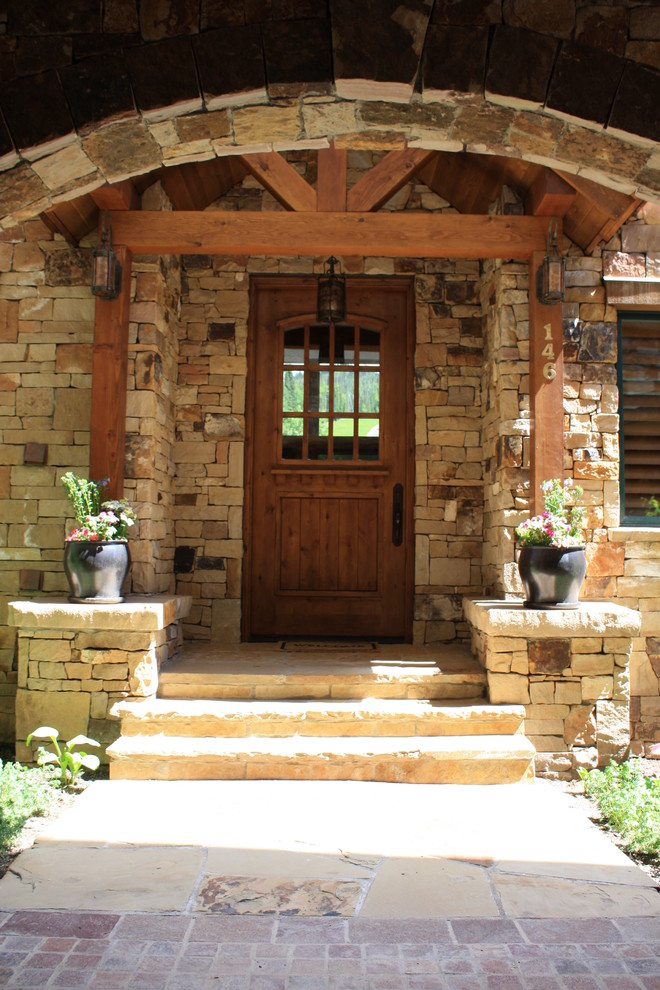 Cette image montre une porte d'entrée chalet de taille moyenne avec une porte simple, une porte en bois foncé et un mur beige.