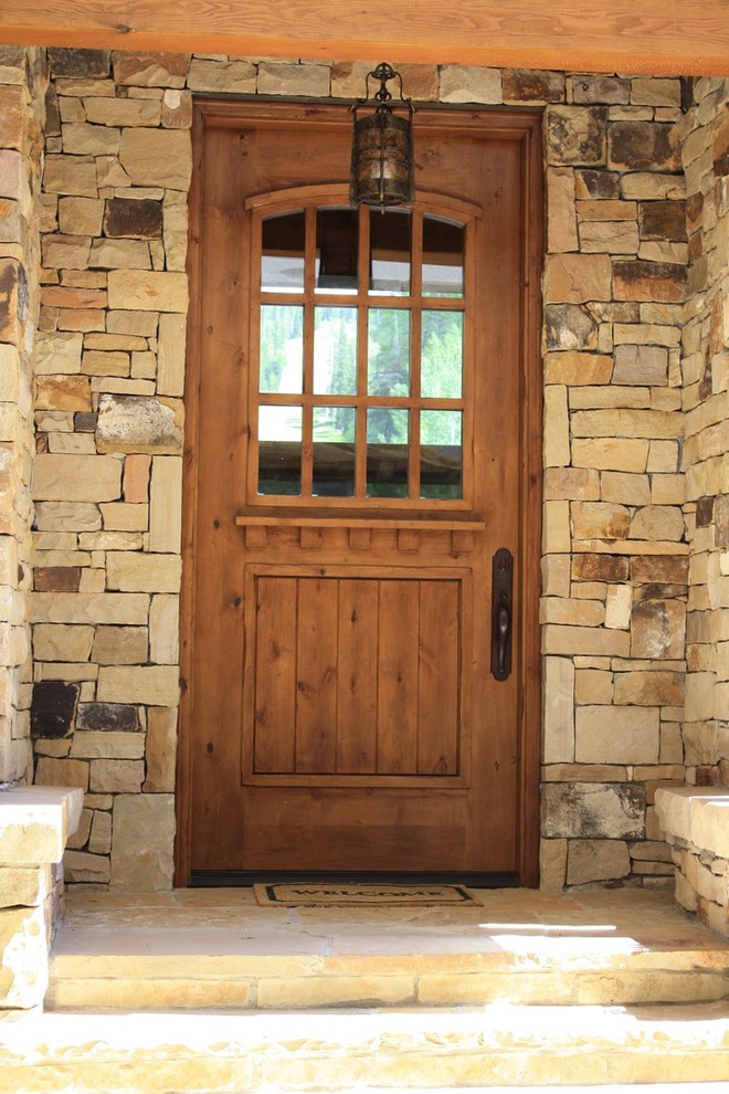 Immagine di una grande porta d'ingresso rustica con pareti multicolore, una porta singola e una porta in legno bruno