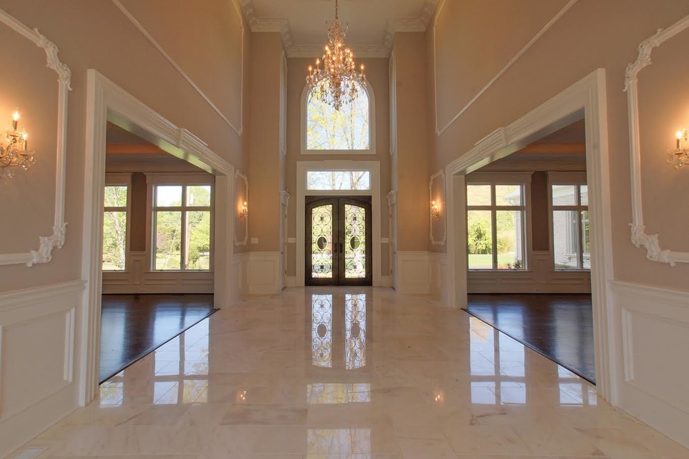 This is an example of an expansive traditional hallway in DC Metro with beige walls, a double front door, a glass front door and grey floors.