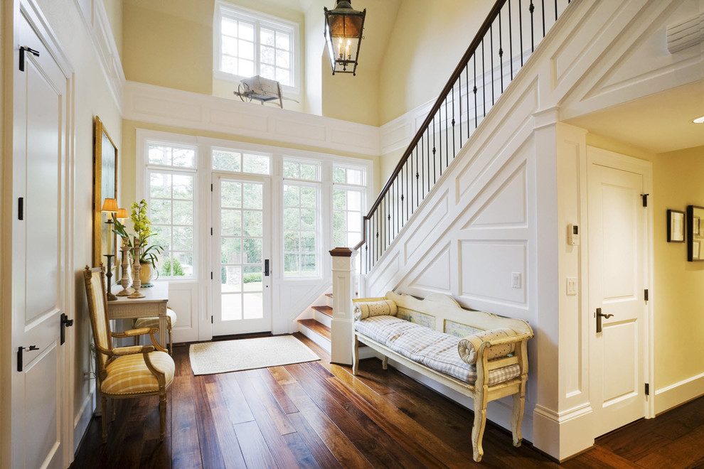 Inspiration for a mid-sized transitional dark wood floor and brown floor entryway remodel in Albuquerque with yellow walls and a white front door