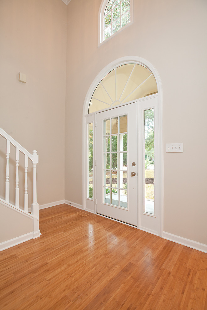 Example of a large classic medium tone wood floor entryway design in Other with beige walls and a white front door
