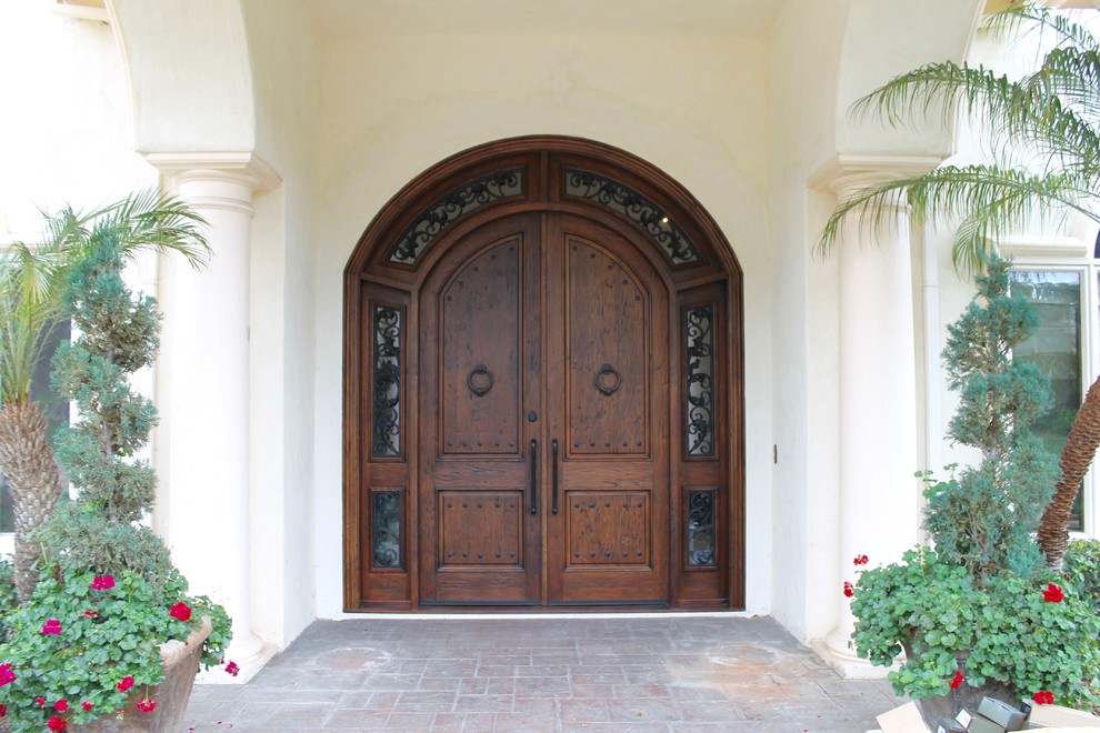 Cette image montre une porte d'entrée méditerranéenne de taille moyenne avec une porte double et une porte en bois foncé.