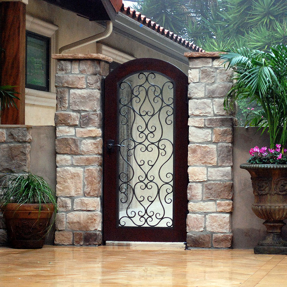 Small mediterranean entrance in Orange County with a single front door and a metal front door.