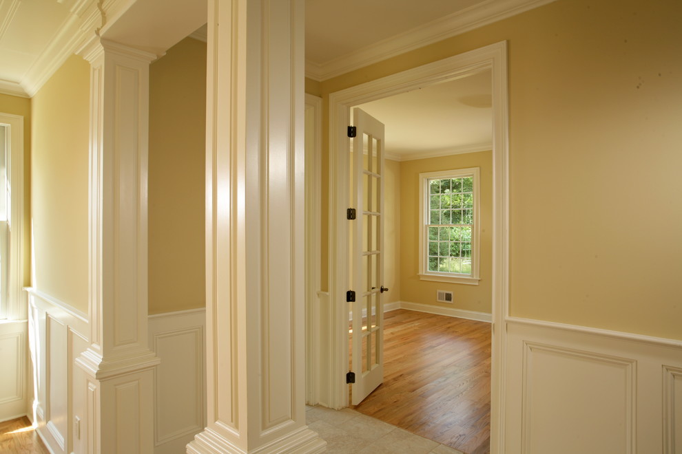 На фото: входная дверь среднего размера в классическом стиле с паркетным полом среднего тона, коричневым полом, бежевыми стенами, одностворчатой входной дверью и белой входной дверью
