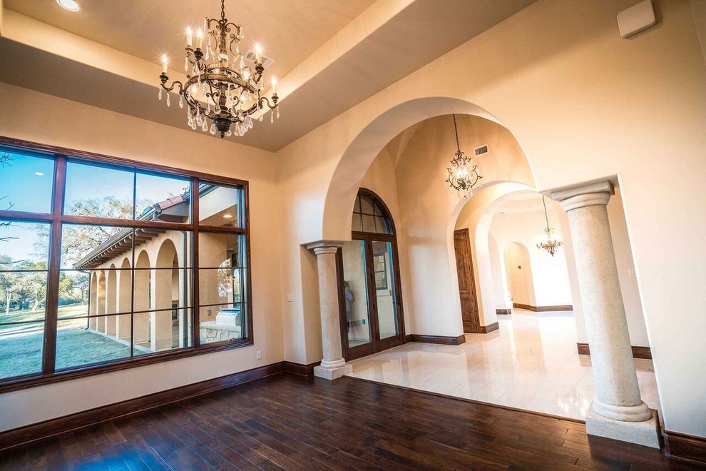 Example of a large tuscan dark wood floor and brown floor entryway design in Austin with beige walls and a glass front door