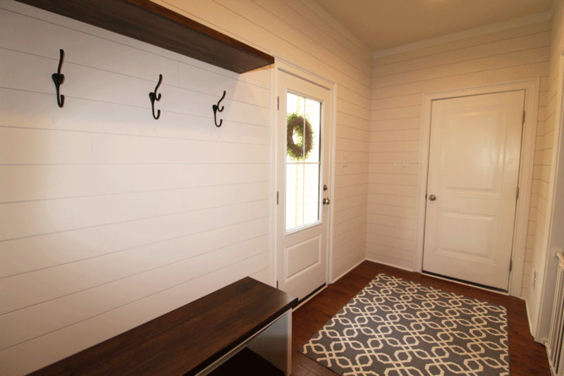 Modelo de vestíbulo posterior de estilo de casa de campo de tamaño medio con paredes blancas, suelo de madera oscura, puerta simple, puerta blanca y suelo marrón