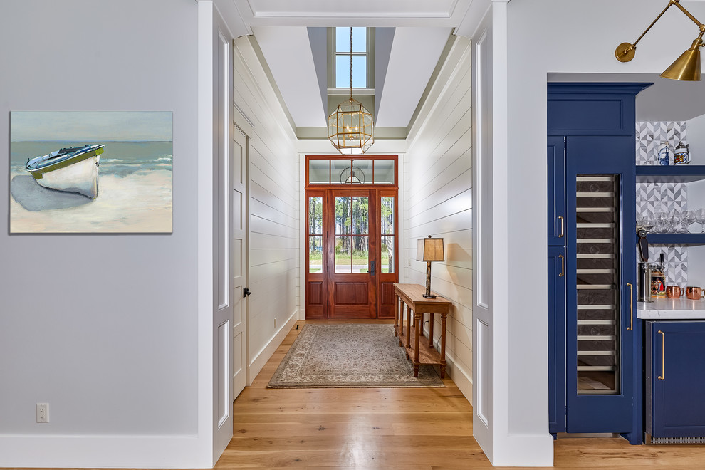 Réalisation d'une grande porte d'entrée minimaliste avec un mur bleu, parquet clair, une porte simple, une porte en bois brun et un sol marron.