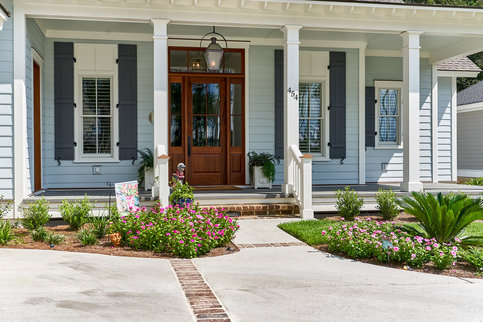 Große Maritime Haustür mit Einzeltür, hellbrauner Holzhaustür, blauer Wandfarbe, Betonboden und weißem Boden in Charleston