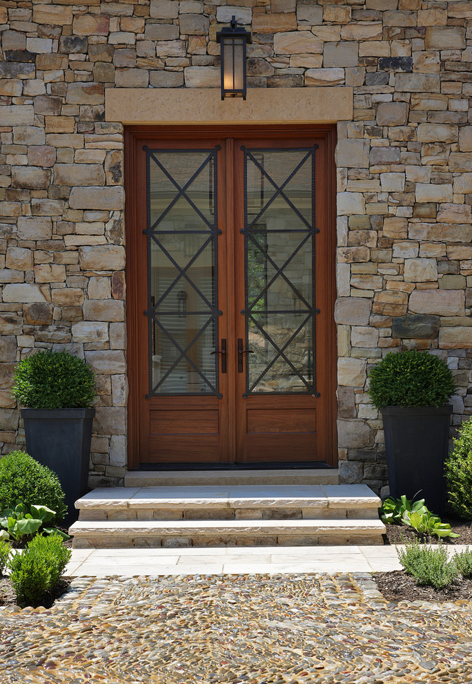 На фото: входная дверь в средиземноморском стиле с двустворчатой входной дверью и входной дверью из дерева среднего тона