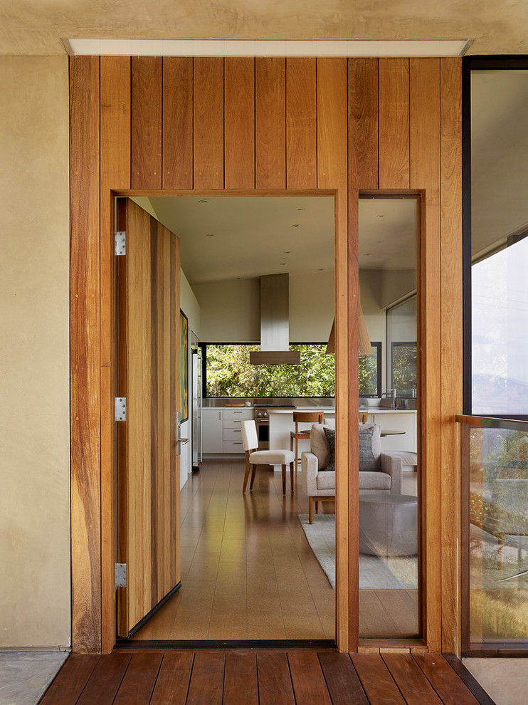 Imagen de puerta principal moderna pequeña con paredes beige, suelo de corcho, puerta simple y puerta de madera en tonos medios