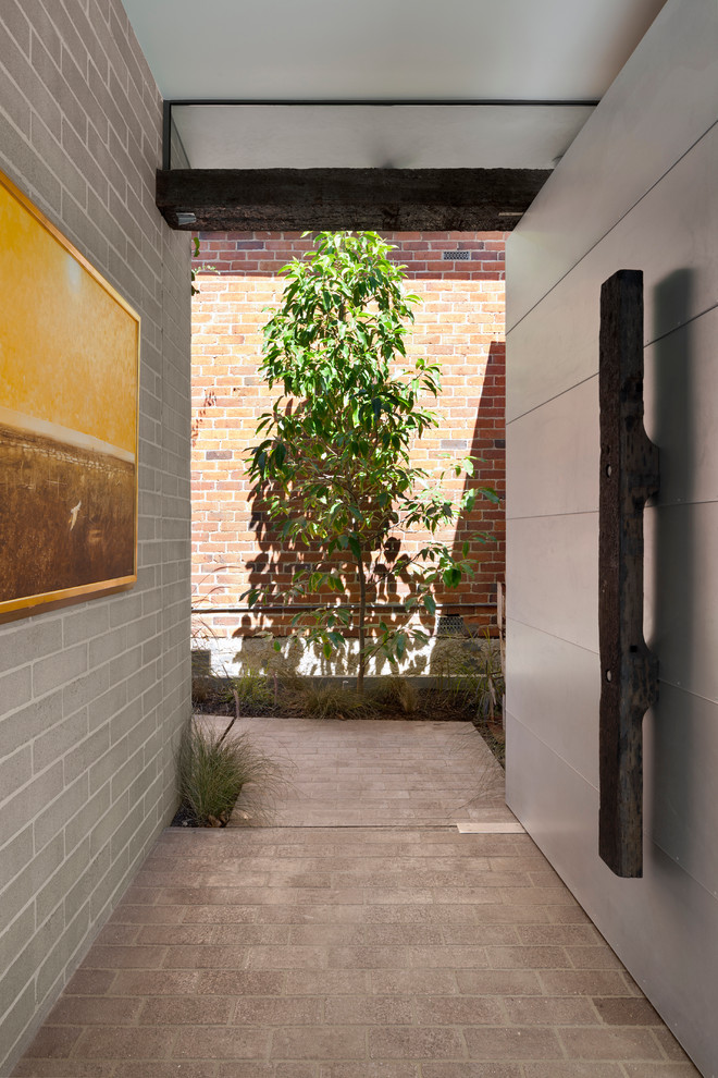 Exemple d'une entrée moderne avec un sol en brique et une porte pivot.