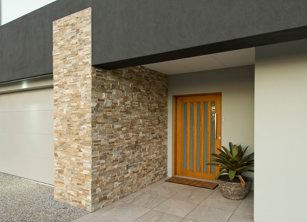 Idées déco pour une grande porte d'entrée moderne avec un sol en carrelage de céramique, une porte pivot, une porte en bois clair et un sol beige.