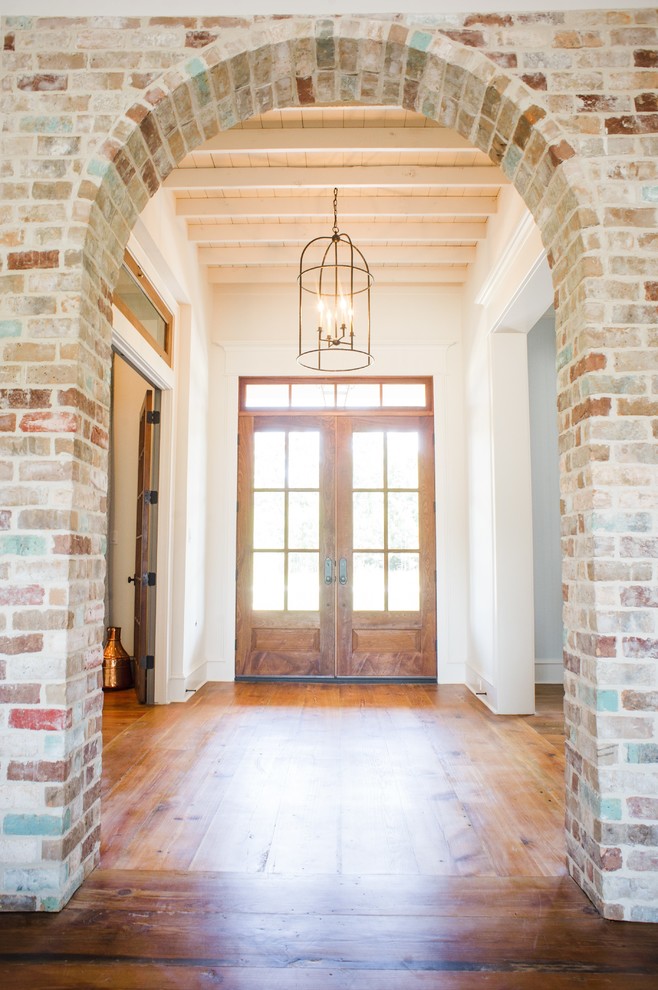 Esempio di un ingresso chic di medie dimensioni con pareti bianche, pavimento in legno massello medio, una porta a due ante, una porta in legno bruno e pavimento marrone