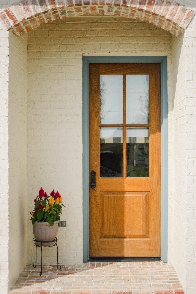 На фото: маленький тамбур в классическом стиле с белыми стенами, кирпичным полом, входной дверью из дерева среднего тона и разноцветным полом для на участке и в саду с