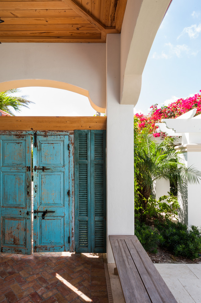 Esempio di una grande porta d'ingresso tropicale con pavimento in mattoni, una porta a due ante e una porta blu