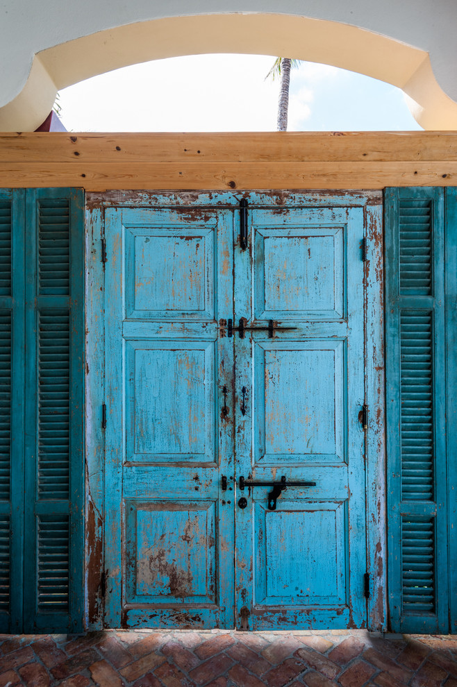 Immagine di una grande porta d'ingresso tropicale con pavimento in mattoni, una porta a due ante e una porta blu