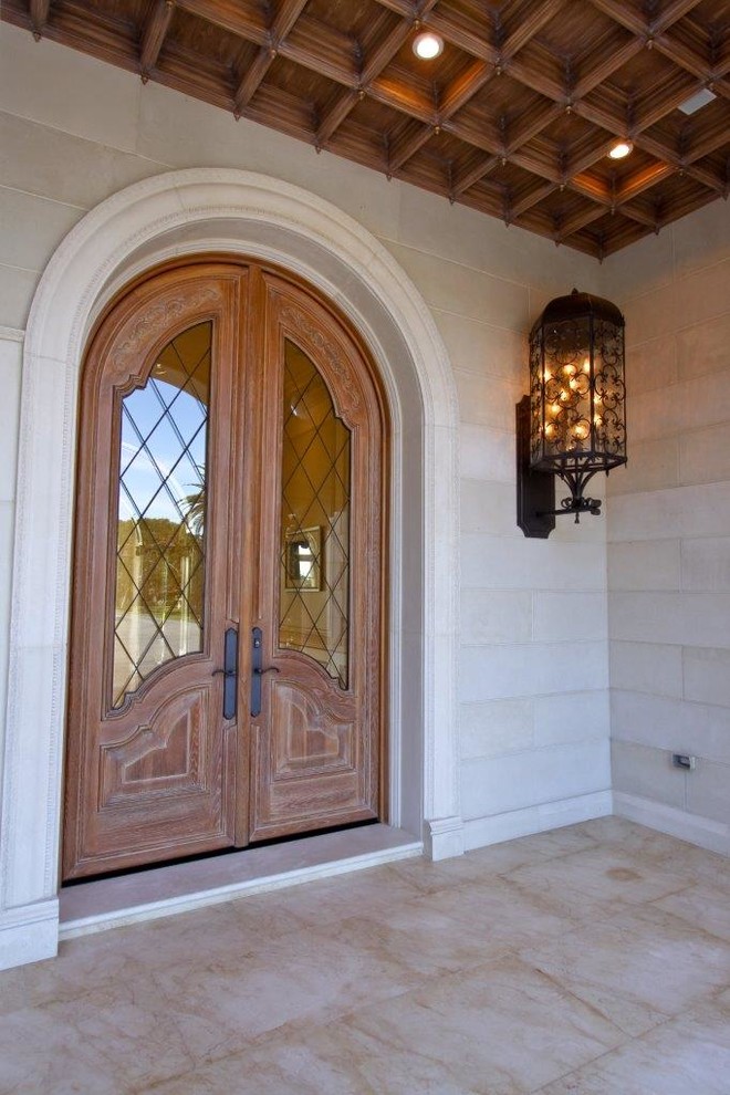 Idée de décoration pour une grande porte d'entrée méditerranéenne avec un mur blanc, un sol en marbre, une porte double, une porte en bois foncé et un sol marron.