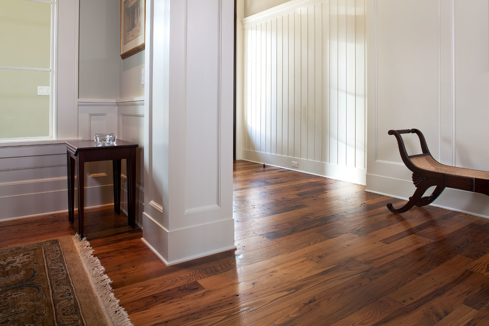 Example of a large classic medium tone wood floor foyer design in Charleston with white walls
