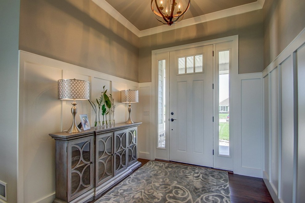 Réalisation d'une porte d'entrée tradition de taille moyenne avec un mur beige, un sol en bois brun, une porte simple et une porte blanche.