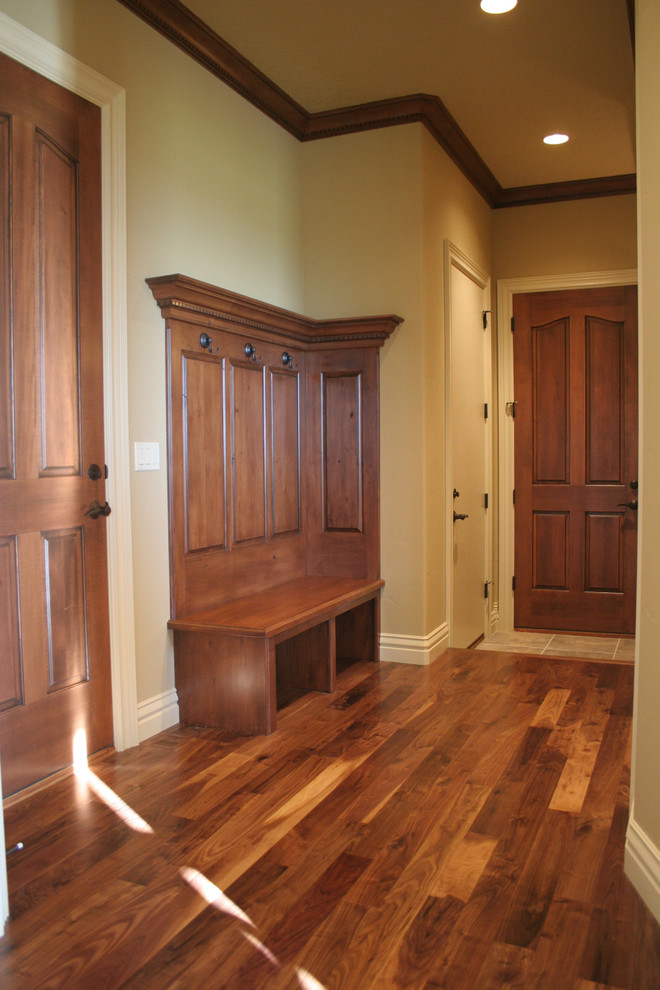 Cette photo montre une entrée chic de taille moyenne avec un mur beige, parquet foncé, un vestiaire, une porte simple, une porte en bois foncé et un sol marron.