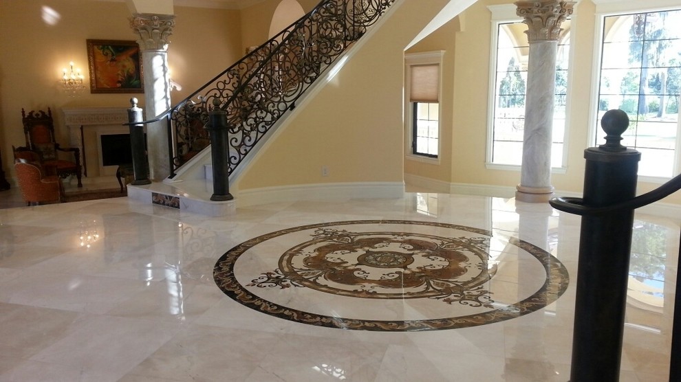 Idée de décoration pour un grand hall d'entrée tradition avec un mur beige, un sol en marbre et une porte double.