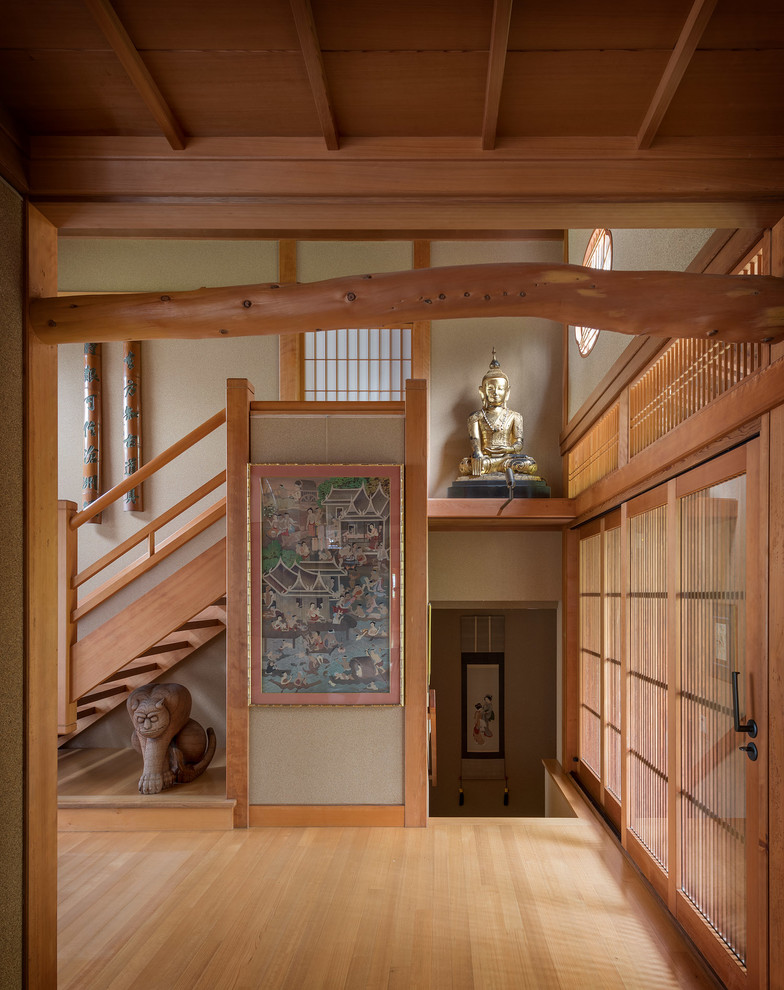 Cette photo montre un hall d'entrée asiatique avec un mur beige, parquet clair, une porte en bois clair et un sol beige.