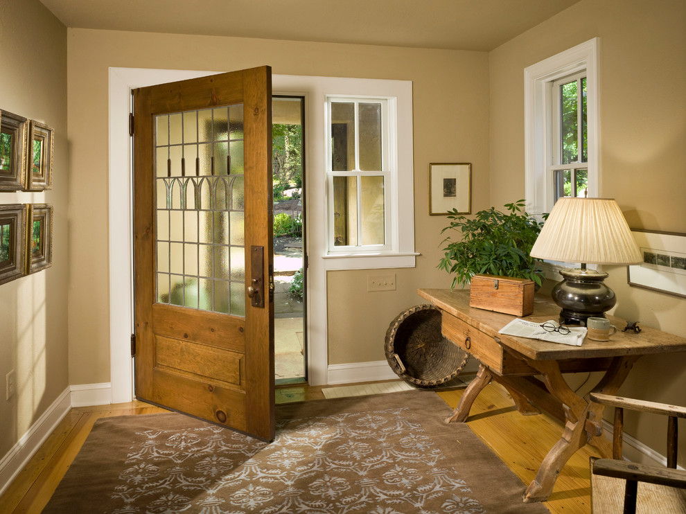 Modelo de distribuidor tradicional grande con paredes beige, suelo de madera en tonos medios, puerta simple y puerta de madera en tonos medios