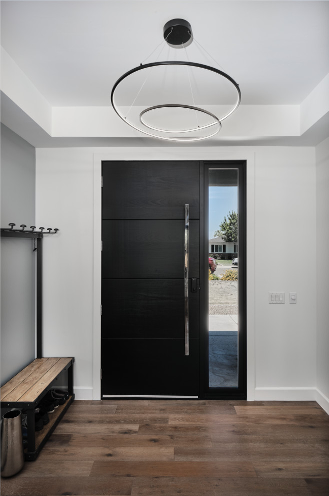 Idée de décoration pour un hall d'entrée minimaliste de taille moyenne avec un mur blanc, un sol en bois brun, une porte simple, une porte noire et un sol marron.