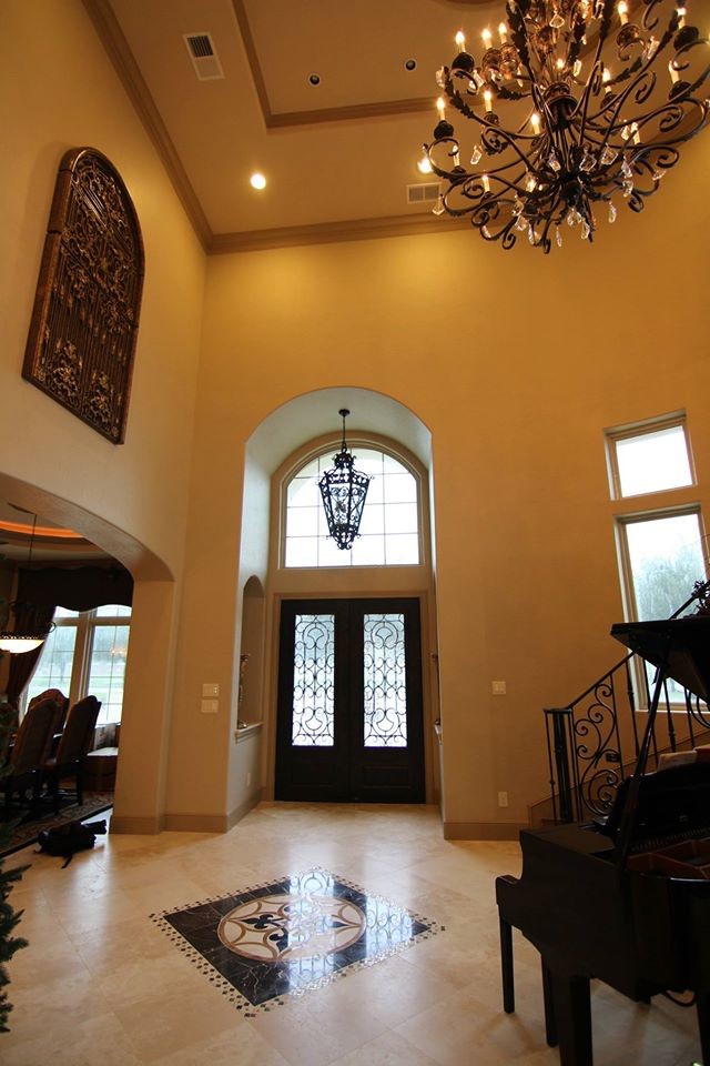 Exemple d'un hall d'entrée chic avec un mur beige, un sol en travertin, une porte double et une porte métallisée.