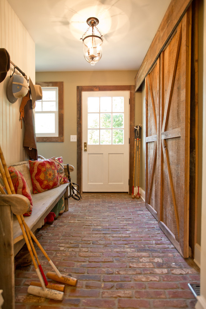 Ejemplo de vestíbulo posterior de estilo de casa de campo con suelo de ladrillo, puerta simple, puerta blanca, paredes beige y suelo rojo