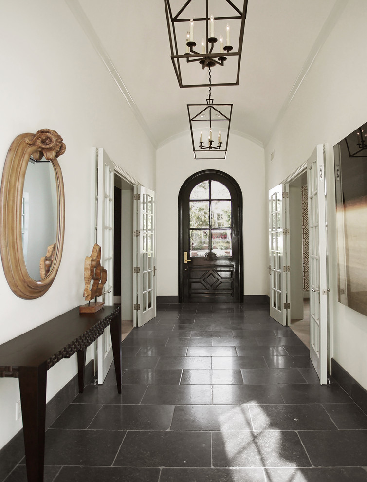 フェニックスにある広いトランジショナルスタイルのおしゃれな玄関 (白い壁、ライムストーンの床、黒いドア、黒い床) の写真