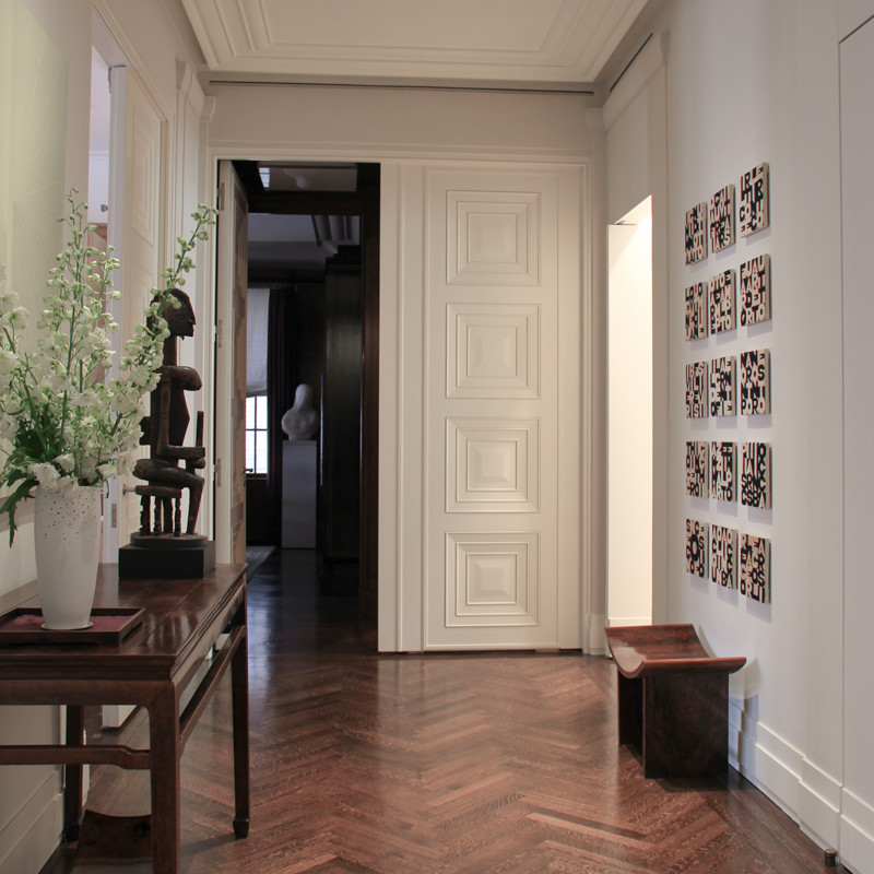 Ejemplo de distribuidor actual de tamaño medio con paredes blancas, suelo de madera en tonos medios, puerta simple y puerta blanca