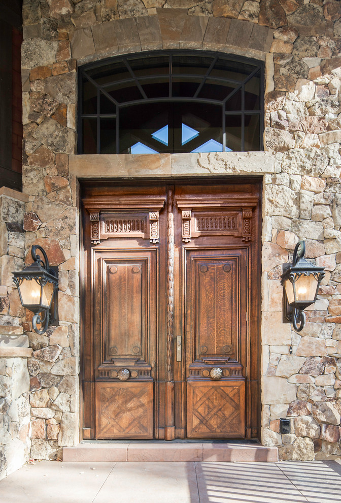 Immagine di un'ampia porta d'ingresso stile rurale con pareti marroni, pavimento in cemento, una porta a due ante e una porta in legno bruno