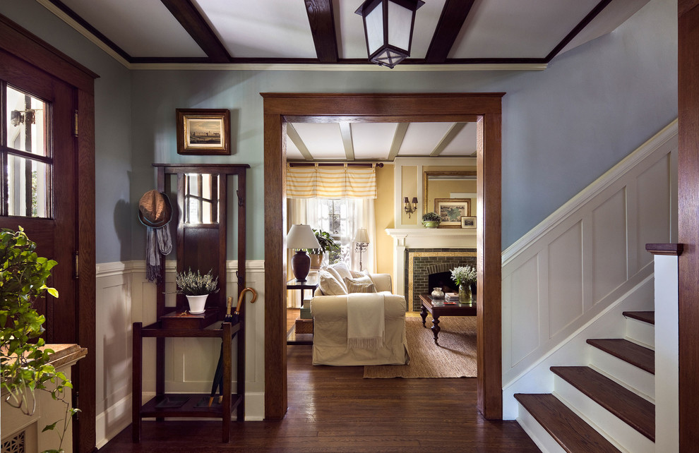 Inspiration for a traditional foyer in New York with blue walls, dark hardwood flooring, a single front door, a dark wood front door, brown floors and feature lighting.