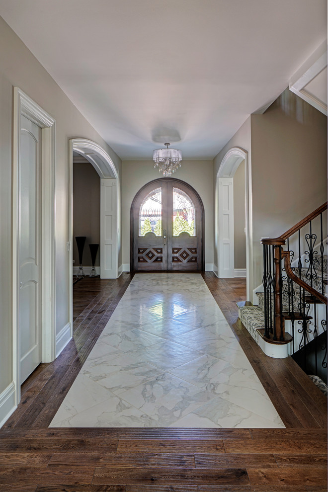 Esempio di un grande ingresso classico con pareti grigie, pavimento in legno massello medio, una porta a due ante, una porta in legno scuro e pavimento marrone