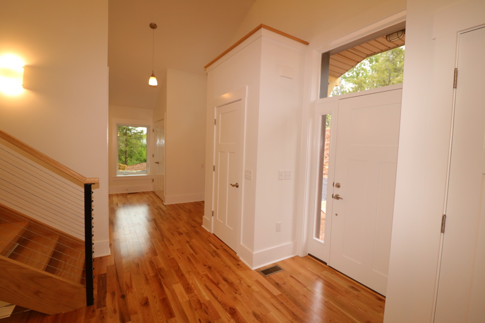 Idee per una porta d'ingresso moderna di medie dimensioni con pareti bianche, pavimento marrone, pavimento in legno massello medio, una porta singola e una porta bianca